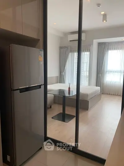 Modern studio apartment with glass partition, featuring a sleek kitchen and cozy bedroom area.