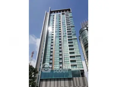 Modern high-rise building with glass facade and clear blue sky backdrop.