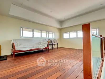 Spacious room with wooden flooring and large windows, perfect for a cozy living area.