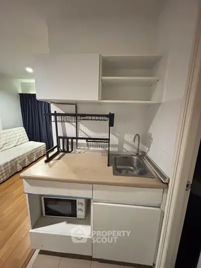 Compact kitchen with microwave and sink in modern apartment