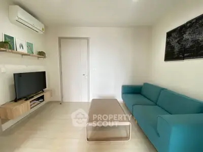 Modern living room with teal sofa, wall-mounted TV, and minimalist decor.