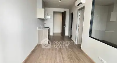Modern minimalist kitchen with sleek cabinetry and wood flooring in a compact apartment.