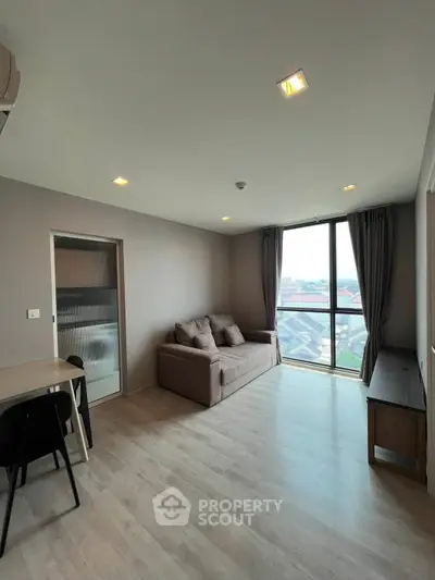 Modern living room with large window and stylish furniture in a high-rise apartment.