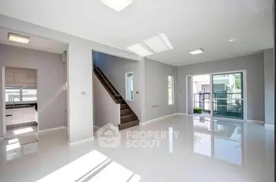 Spacious modern living room with glossy floors and natural light, featuring a staircase and balcony access.