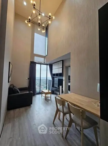 Modern high-ceiling living room with stylish chandelier and balcony view.