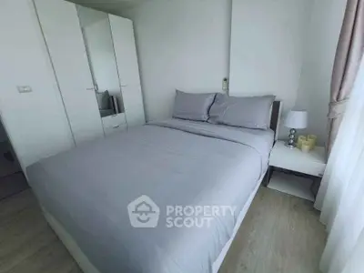 Cozy modern bedroom with stylish gray bedding and ample natural light.