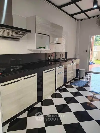 Modern kitchen with sleek cabinetry and black-and-white checkered flooring
