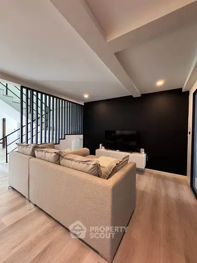 Modern living room with sleek black accent wall and cozy beige sofa, perfect for relaxation and entertainment.