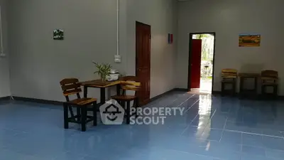 Spacious interior with blue tiled floor and wooden furniture, featuring an open door to a lush garden.