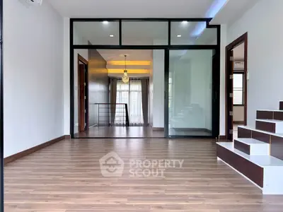 Spacious modern living room with wooden flooring and glass partition, perfect for stylish urban living.