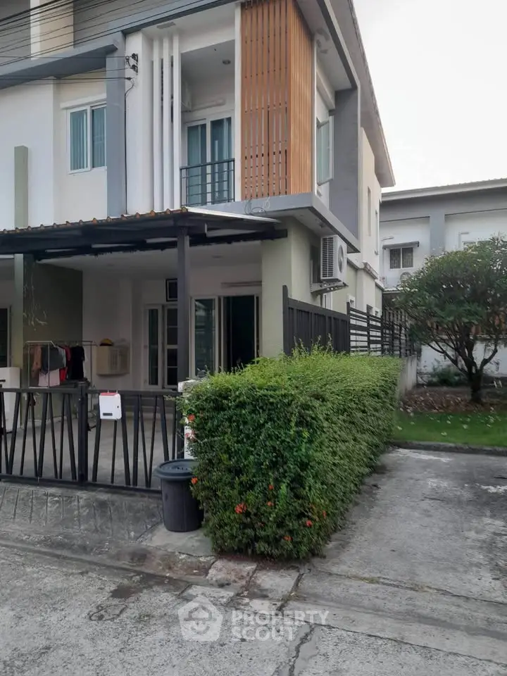 Modern two-story townhouse with gated entrance and lush greenery in a serene neighborhood.