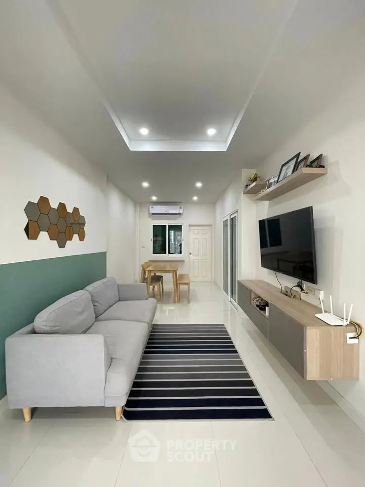 Modern living room with sleek furniture and stylish decor, featuring a cozy gray sofa and wall-mounted TV.