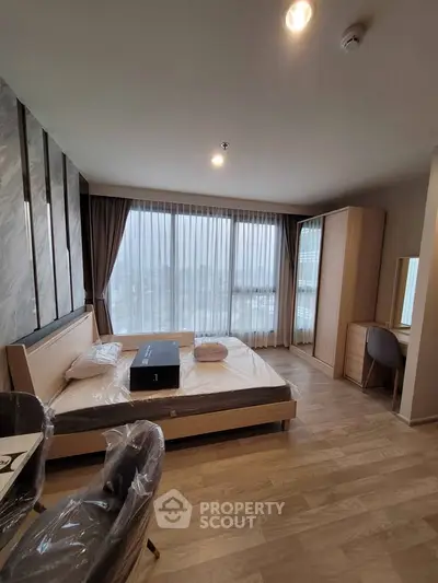 Modern bedroom with large window and stylish furnishings in a high-rise apartment.