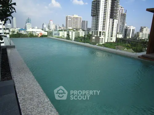 Luxurious rooftop infinity pool with stunning city skyline views in a modern high-rise building.