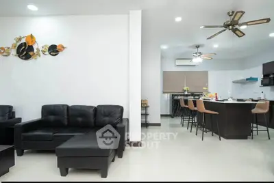 Spacious modern living room with open kitchen, sleek black furniture, and stylish decor.