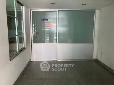 Spacious empty office space with glass partition and natural light.