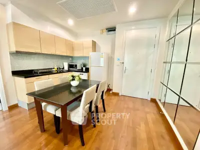 Modern kitchen with dining area featuring wooden floors and sleek cabinetry.