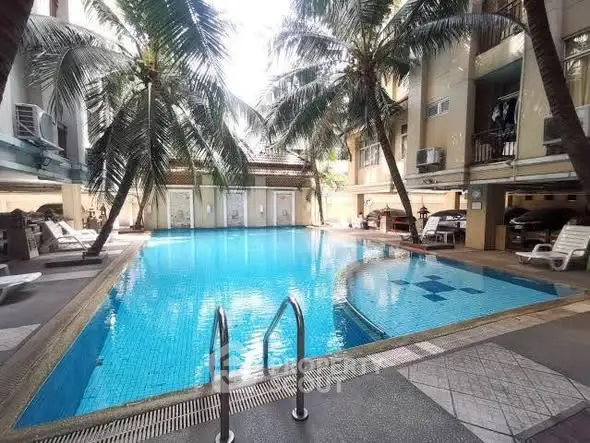 Luxurious residential pool area with palm trees and lounge chairs, perfect for relaxation and leisure.