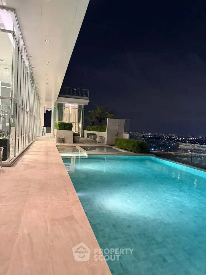 Luxurious rooftop pool with stunning city skyline view at night, perfect for relaxation and entertainment.