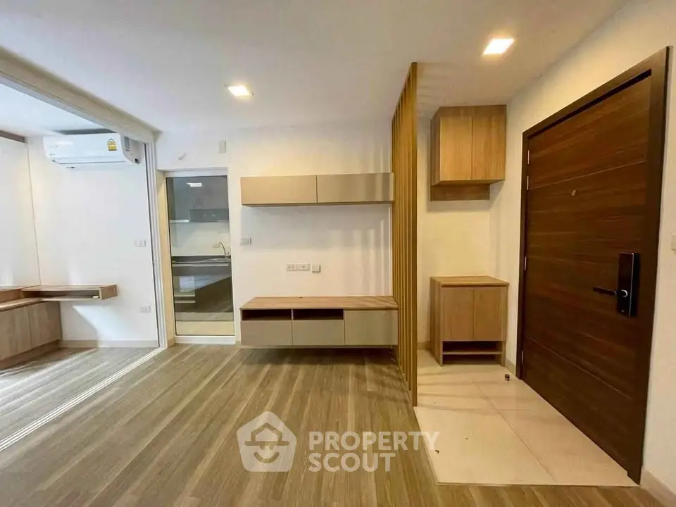 Modern interior with wooden flooring and built-in storage, featuring a sleek kitchen area.