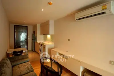 Modern living room with integrated kitchen and sleek furniture in a cozy apartment.