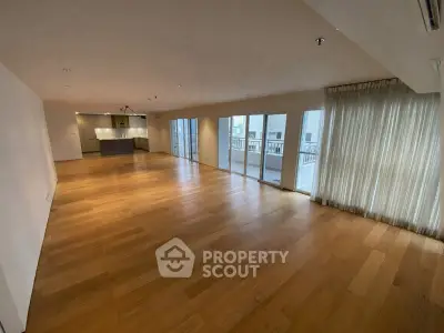 Spacious open-plan living room with wooden flooring and balcony access.