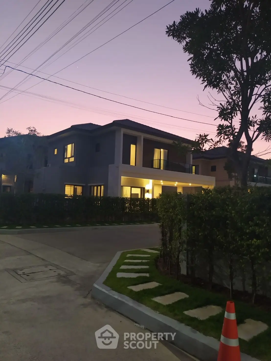 Stunning modern house exterior at dusk with warm lighting and lush landscaping.