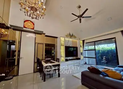 Luxurious living room with high ceiling, elegant chandelier, and modern decor in a spacious open layout.