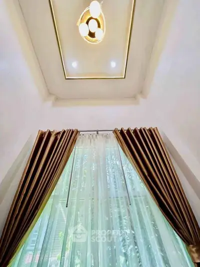 Elegant high ceiling with modern lighting and luxurious curtains in a stylish home interior.
