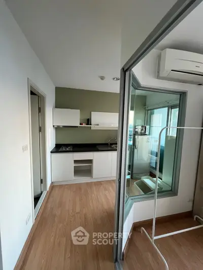 Modern apartment with sleek kitchen and balcony view, featuring wooden flooring and air conditioning.