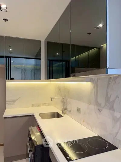 Modern kitchen with sleek design, featuring induction cooktop and under-cabinet lighting.