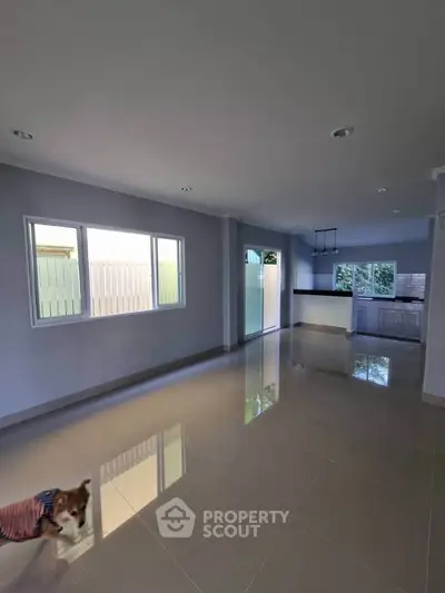 Spacious open-plan living area with modern kitchen and glossy tiled floors.