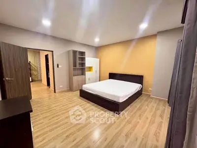 Spacious modern bedroom with wooden flooring and stylish furniture