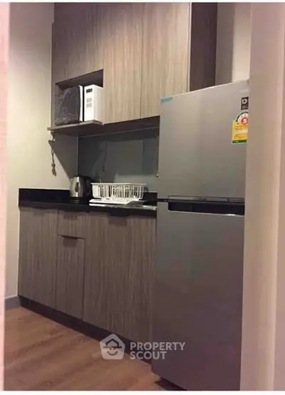 Modern compact kitchen with sleek cabinetry and stainless steel fridge