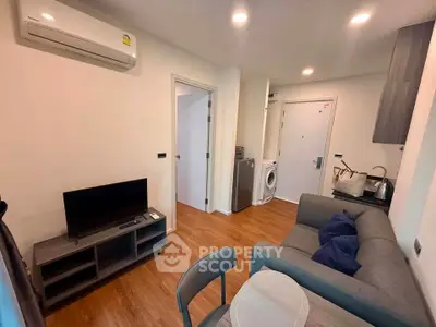 Modern living room with wooden flooring, cozy sofa, and compact kitchen area.