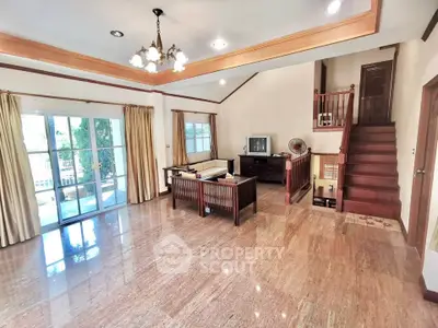 Spacious living room with elegant wooden staircase and large windows for natural light.