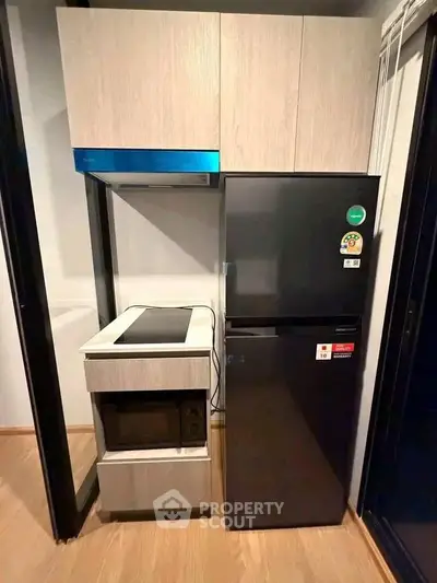 Modern kitchen with sleek appliances and compact design, featuring a refrigerator and built-in stove.