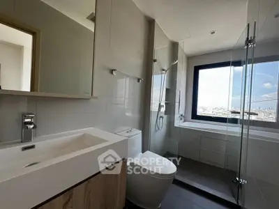 Modern bathroom with city view, featuring sleek fixtures and glass shower enclosure.