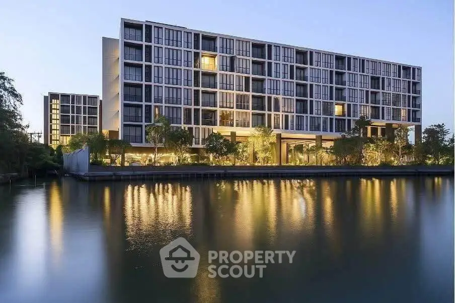 Stunning modern apartment building with waterfront view and lush greenery, perfect for luxury living.
