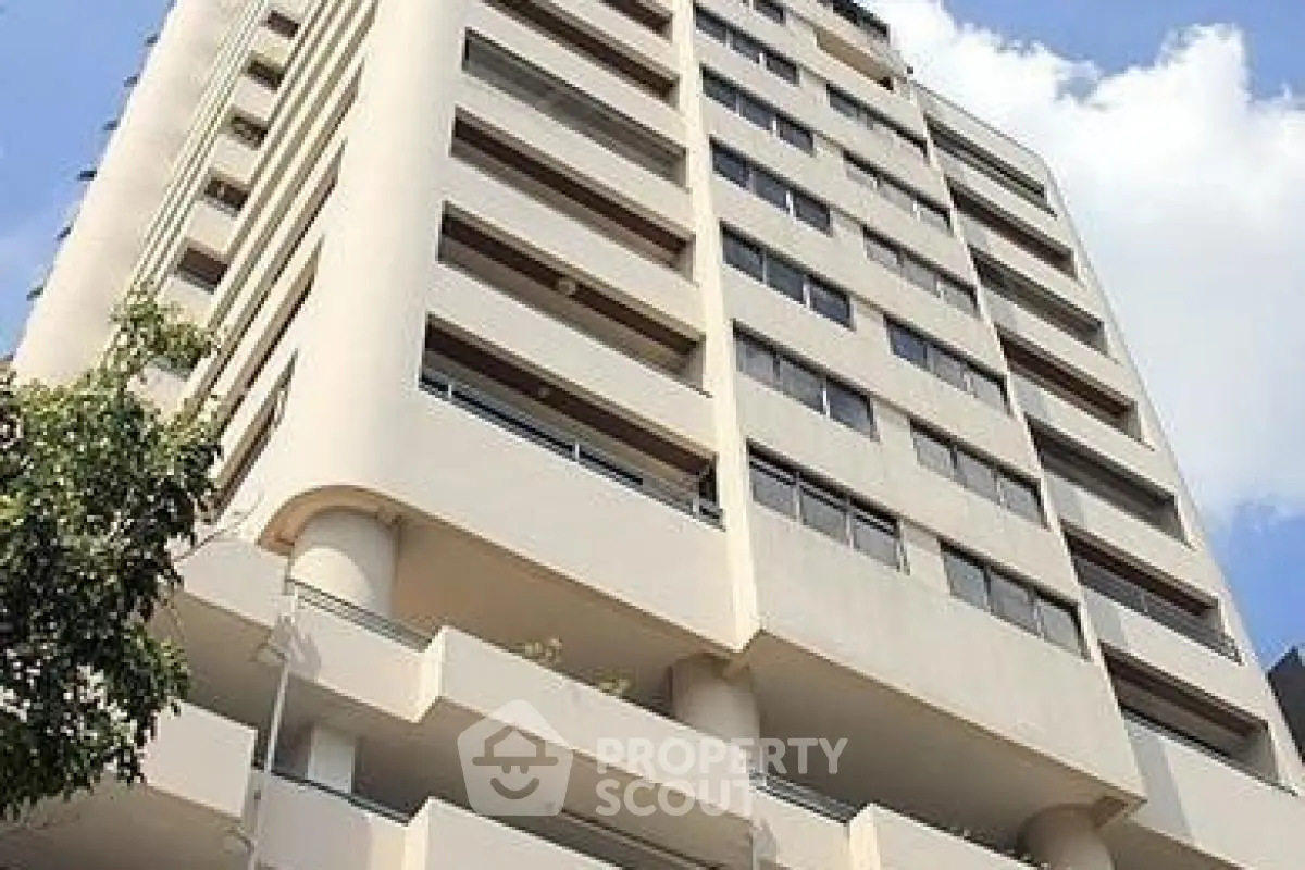 Modern high-rise building with sleek architecture and spacious balconies in urban setting.