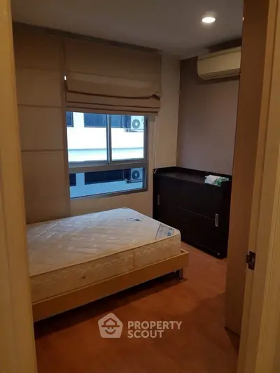 Cozy bedroom with wooden flooring and air conditioning, perfect for a restful retreat.