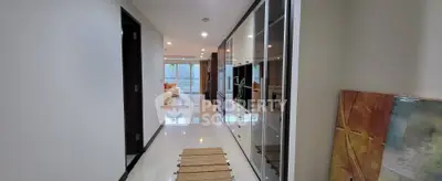 Spacious modern hallway leading to a bright living room with stylish decor and large windows.