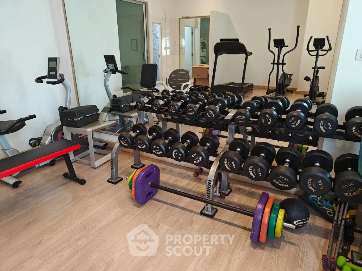 Spacious home gym with modern equipment and weights, perfect for fitness enthusiasts.