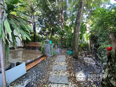 Charming garden with lush greenery and stone pathway, perfect for relaxation and outdoor enjoyment.