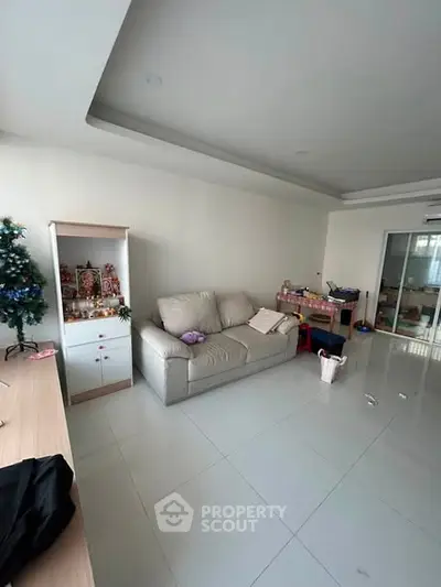 Spacious living room with modern sofa and sleek tiled flooring, perfect for family gatherings.