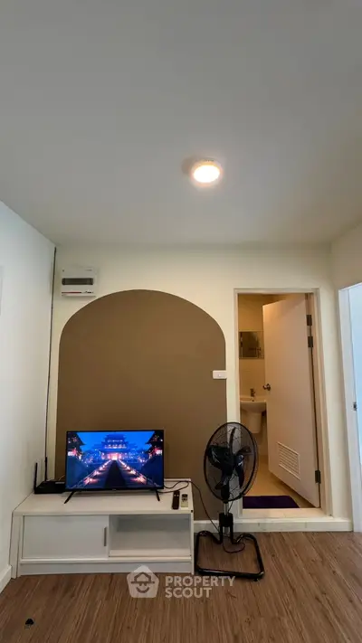 Modern living room with TV and fan, featuring a stylish arch design and wooden flooring.