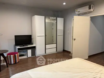 Spacious bedroom with modern wardrobe and TV unit, featuring elegant wooden flooring.