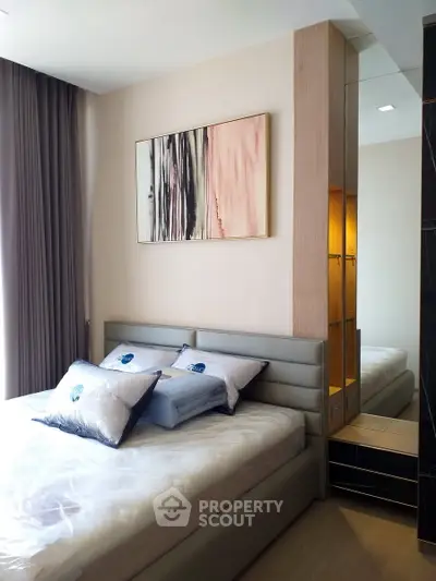Modern bedroom with stylish decor and natural light, featuring a comfortable bed and elegant artwork.