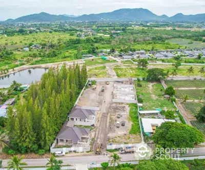 Aerial view of residential development with lush greenery and mountain backdrop.