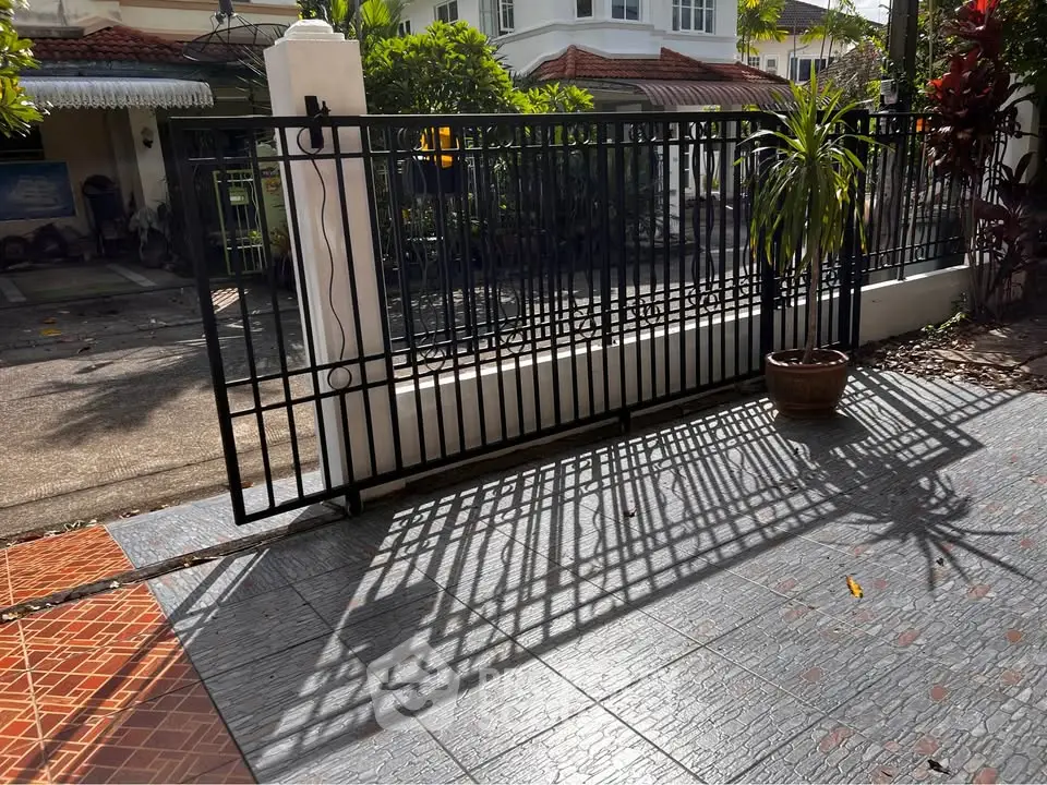 Charming residential entrance with elegant wrought iron gate and lush greenery